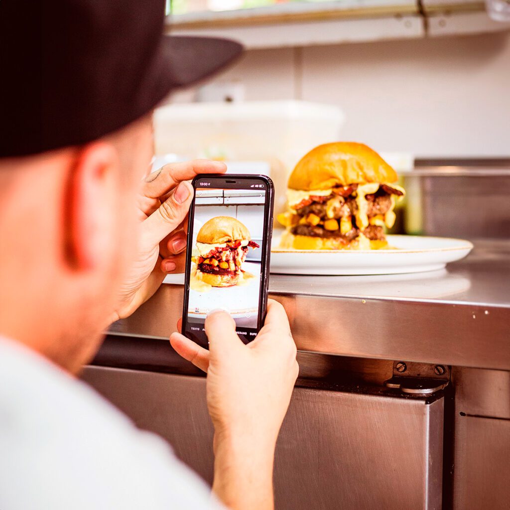 Homem produzindo fotografias para comunicações baseadas em estratégias de marketing digital|Fachada de um restaurante de alto padrão, com um balconista a postos.|Fotografia de uma unidade do Burger King em uma ação de marketing para o Halloween.